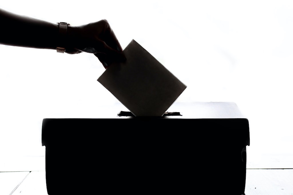una mano mette una scheda elettorale nell'urna